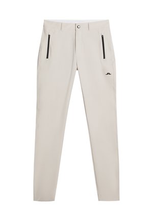 Pantalons slim fit beiges en tissu léger ; dotés de poches zippées noires et d'un petit logo près de la taille.