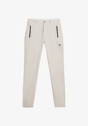 Pantaloni beige slim-fit realizzati in tessuto leggero; presentano tasche con zip nere e un piccolo logo vicino alla vita.