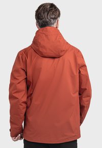 Rode waterbestendige jas met capuchon, met een gladde textuur en een eenvoudig ontwerp. De achterkant heeft geen zichtbare logo's of versieringen.
