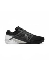 Scarpe da ginnastica nere con una tomaia in rete, tessuto testurizzato e una suola in gomma bianca e grigia a contrasto. Presentano lacci piatti e un design che offre supporto.