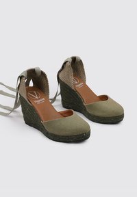 Sandales compensées en toile verte avec une semelle en jute texturé, design à talon ouvert et fines lanières pour un maintien sûr. Semelle intérieure marron avec détail de logo.