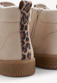 Béžové kotníkové boty s hnědými gumovými podrážkami, s leopardím vzorem na poutkách a bočními zipy, podšité jemným bílým fleecem.