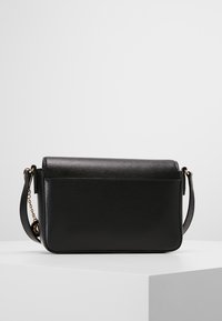 Borsa a tracolla nera in pelle testurizzata con forma rettangolare slim, hardware dorato e tracolla a catena rimovibile.