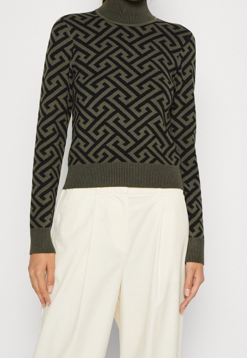 Turtleneck-Pullover in Olivgrün mit einem geometrischen schwarzen Muster. Gerippte Bündchen und Saum, aus einem weichen Strickmaterial gefertigt.