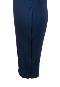 Nahaufnahme des Unterschenkels einer marineblauen Hose mit sichtbarer Seitennähten und umgenähtem Saum.
