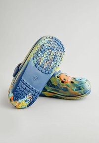 Sabots colorés en matériau flexible, avec une base bleue ornée de tourbillons multicolores, des trous de ventilation et des boutons décoratifs.