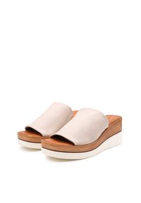 Scarpe slip-on in pelle beige con una parte superiore ampia e morbida e un tacco a cuneo affusolato. La suola presenta un accento bianco e un motivo di grip testurizzato.