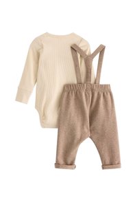 Béžový bodysuit s dlouhým rukávem a ribbovanou texturou, spárovaný s hnědými kalhotami s ohrnutými manžetami a nastavovacími kšandami.