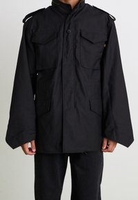 Czarna kurtka wierzchnia z długimi rękawami, dwoma przednimi kieszeniami z klapami, zapięciem na guziki oraz naramiennikami. Wykonana z teksturowanej tkaniny.