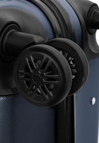 Ruedas de plástico negro unidas a una maleta azul texturizada, con un cierre prominente y un diseño de rodaje suave para una fácil maniobrabilidad.