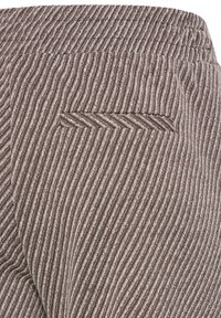 Gros plan sur un pantalon à rayures marron et blanches avec une poche passepoilée horizontale et une taille élastiquée, montrant la texture et les détails du motif.