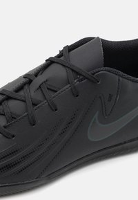 Černá sportovní obuv se syntetickým svrškem, texturovaným designem, šněrováním a nenápadným logem Nike v tmavším odstínu na boku.