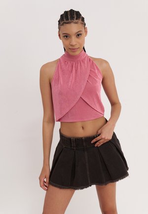 Roze mouwloze top met een hoge kraag, met een geraffineerd design, gecombineerd met een zwarte jeansrok met plooien en een rafelige zoom.