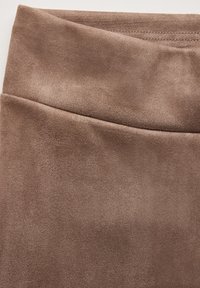 Leggings in similpelle marrone con una texture liscia, vita elastica e un design aderente con minimi dettagli di cucitura.