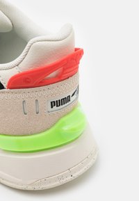 Takapuolet bejža Puma kedar, crimson heela klips, neonroheline keskosa aktsent ja tekstuurne valge talla.