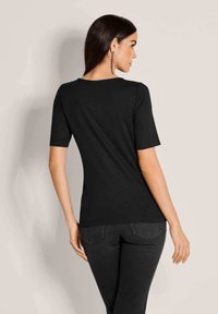 Schwarzes kurzärmliges Oberteil mit lockerer Passform, aus einem glatten Stoff gefertigt. Verfügt über einen runden Halsausschnitt und einen geraden Saum auf Taillenhöhe.