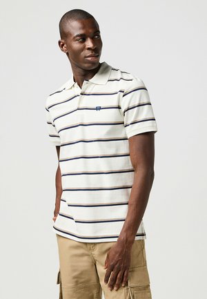 Gestreiftes Poloshirt in Creme mit marineblauen und braunen Streifen. Kurze Ärmel, gerippter Kragen und kleines Logo auf der Brust. Lässige Passform.