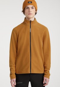 Fleecejacke in Senfgelb mit Stehkragen und schwarzem Reißverschluss. Verfügt über dezente Markenkennzeichnung am Ärmel. Weicher Stoff.