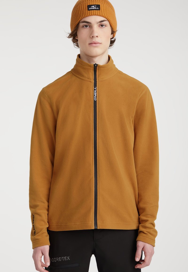 Fleecejacke in Senfgelb mit Stehkragen und schwarzem Reißverschluss. Verfügt über dezente Markenkennzeichnung am Ärmel. Weicher Stoff.