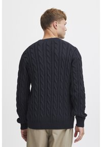 Marineblauer Kabelstrickpullover mit strukturiertem Muster, gerippten Bündchen und Saum. Designed mit einer lässigen Passform und Rundhalsausschnitt.