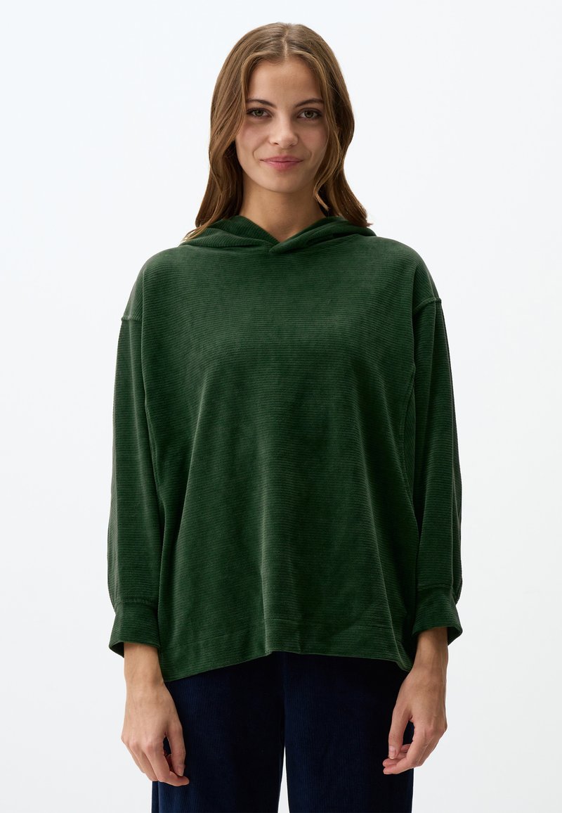 Felpa verde con cappuccio in tessuto testurizzato. Caratterizzata da una vestibilità ampia, spalle scese e polsini. Abbinata a pantaloni scuri e testurizzati.