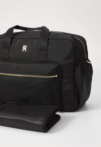 Sacoche pour ordinateur portable noire en nylon avec des accents de fermoir dorés, dotée de deux poignées supérieures et d'une poche zippée à l'avant. Comprend un tapis noir pliable et durable.