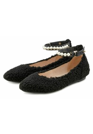 Bailarinas negras de felpa con una superficie texturizada, punta puntiaguda y una correa negra en el tobillo adornada con perlas falsas blancas.