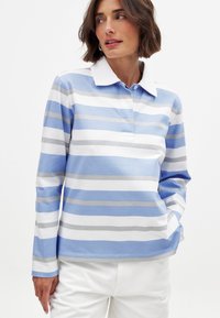 Dlhý rukáv polo tričko v svetlo modrej farbe so bielymi horizontálnymi pruhmi. Obsahuje biely golier a mäkkú bavlnenú tkaninu. Voľný strih.
