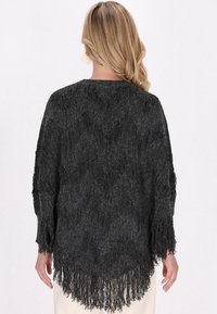 Șal franjurat de culoare gri închis, cu o țesătură texturată. Croială lejeră, cu mâneci lungi și franjuri de lungimi variate la tiv. Design simplu și elegant.