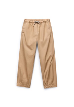 Beige, lightweight, relaxed-fit pants with an elastic waistband and drawstring, featuring side pockets and smooth, slightly shiny texture.