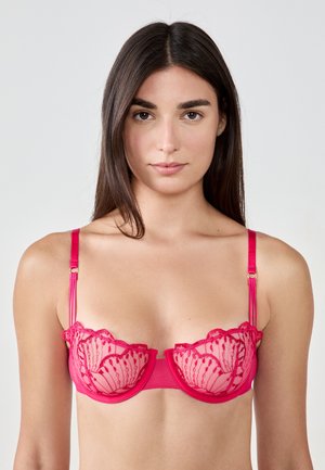 Rosa Spitze-BH mit durchsichtigen Einsätzen, wellenförmigen Kanten und feinen Details. Verfügt über verstellbare Träger und ein glattes Band.