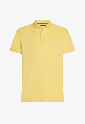 Kollane lühikeste varrukatega polosärk klassikalise kraega, vasakul rinnal väike tikitud logo ja sile, kerge kangas.