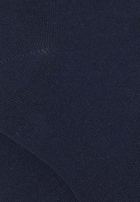 Tessuto a maglia blu navy con una superficie liscia, che mostra un motivo uniforme e un allineamento regolare. Nessun accento visibile o dettagli aggiuntivi.