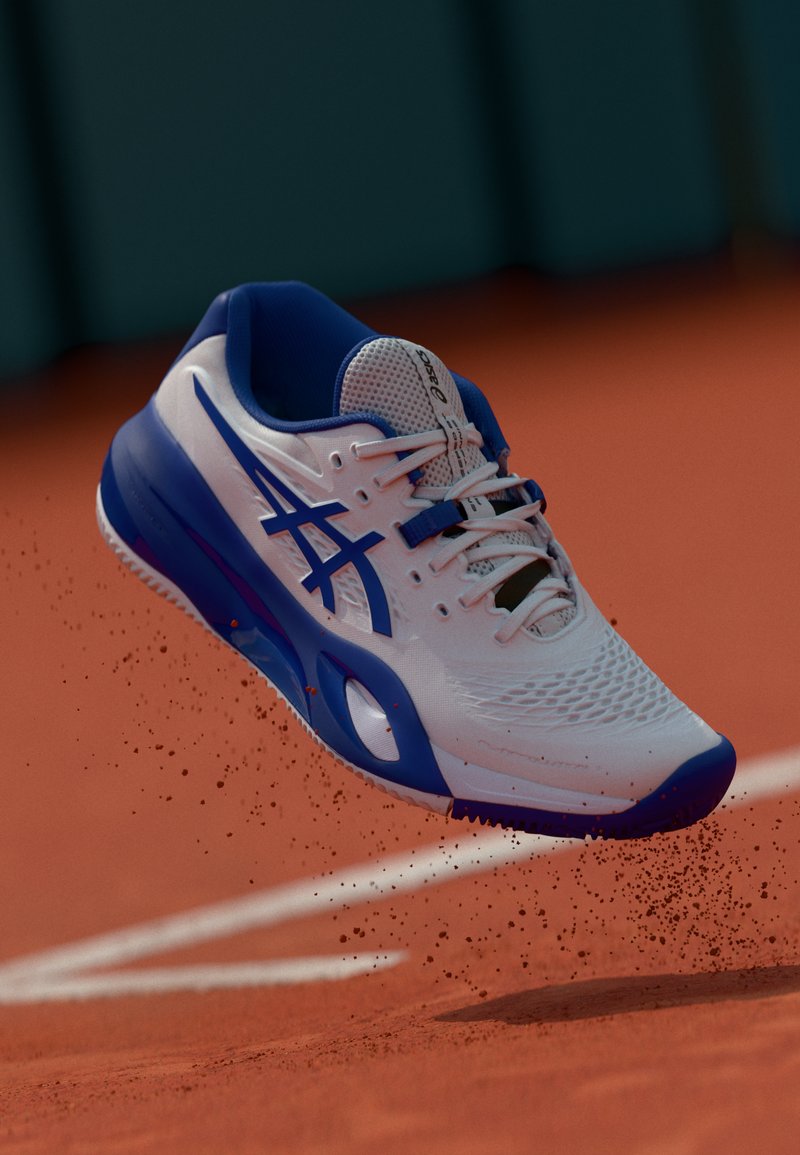 Chaussure de sport blanche et bleue avec une tige en maille, des détails texturés et une semelle en caoutchouc, conçue pour la performance sportive sur un court en terre battue.