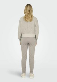 Helles graues Strickpullover mit strukturiertem Muster, kombiniert mit passenden grauen Hosen. Beide haben einen lässigen Schnitt und ein angenehmes Material.
