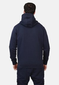 Felpa con cappuccio blu navy dal taglio classico, realizzata in morbido tessuto testurizzato; presenta un ampio cappuccio e polsini a costine.