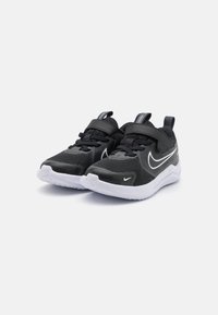 Baskets de sport noires avec tige en mesh, deux sangles, semelle blanche et logo swoosh de Nike. Bout arrondi et tissu texturé pour la respirabilité.