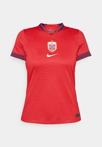 Maillot de football rouge à manches courtes avec un col rond, des accents bleus sur les poignets, et un emblème du drapeau norvégien avec des détails dorés. Logo Nike présent.