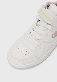 Sneaker en cuir blanc avec un bout rond, des accents texturés, une sangle rose et un logo. Présente des lacets plats et des perforations pour une meilleure respirabilité.