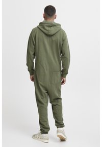 Mono de una pieza verde oliva con capucha, mangas largas, piernas ajustadas y un bolsillo trasero. Fabricado en una tela suave con puños acanalados.
