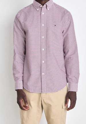 Rood en wit geruite overhemd met knopen, recht kraag, lange mouwen en knoopsluiting. Heeft een contrasterend ruitpatroon.