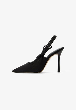 Zapato de tacón alto negro tipo slingback con puntera afilada, parte superior de tela, detalles de encaje y un delgado tacón stiletto. La correa presenta acentos cosidos.