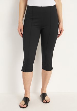 Zwarte 3/4 legging van rekbaar materiaal, met een gladde textuur, een aansluitend ontwerp en decoratieve naden aan de voorkant.