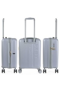 Maleta rígida de color gris claro con un acabado texturizado, ruedas dobles y un mango telescópico. Presenta detalles con logo y un cierre de cremallera.