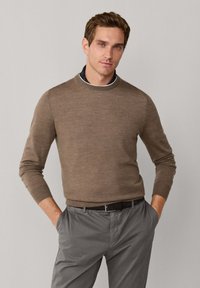 Bruine trui met een ronde hals, aansluitend ontwerp en zachte textuur, gecombineerd met grijze broek en een zwarte riem.