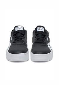 Juodi odiniai sportbačiai su baltais akcentais, turintys apvalią nosį, storą baltą padu ir Reebok logotipą ant liežuvio ir šono.