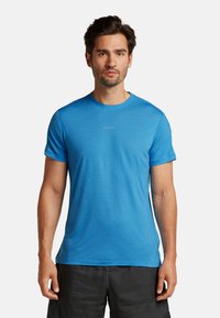 Blå T-shirt med korte ærmer lavet af åndbart stof, med rund hals og en subtil struktur. Logo vist på forsiden.
