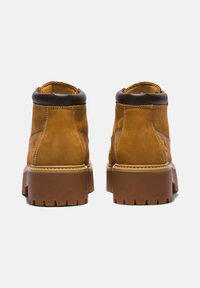 Bruine leren enkellaarzen met een gevoerde kraag, dikke bruine rubberen zool en een gestructureerde afwerking, met zichtbare stiksels en een versterkte hiel.