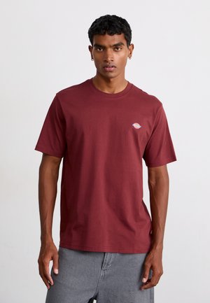 Burgundy cotton T-shirt with short sleeves and round neckline; features small logo detail on the chest. Smooth texture and relaxed fit.