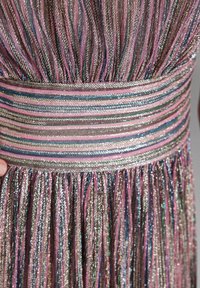 Primer plano de una tela brillante multicolor con rayas verticales y horizontales, mostrando un detalle de cintura ceñida.